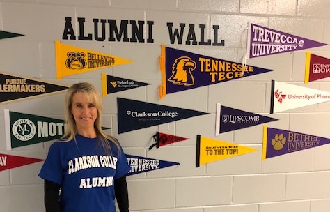 Alumna Joyce Crites ('96) stands near the Clarkson College banner at Westwood Middle School