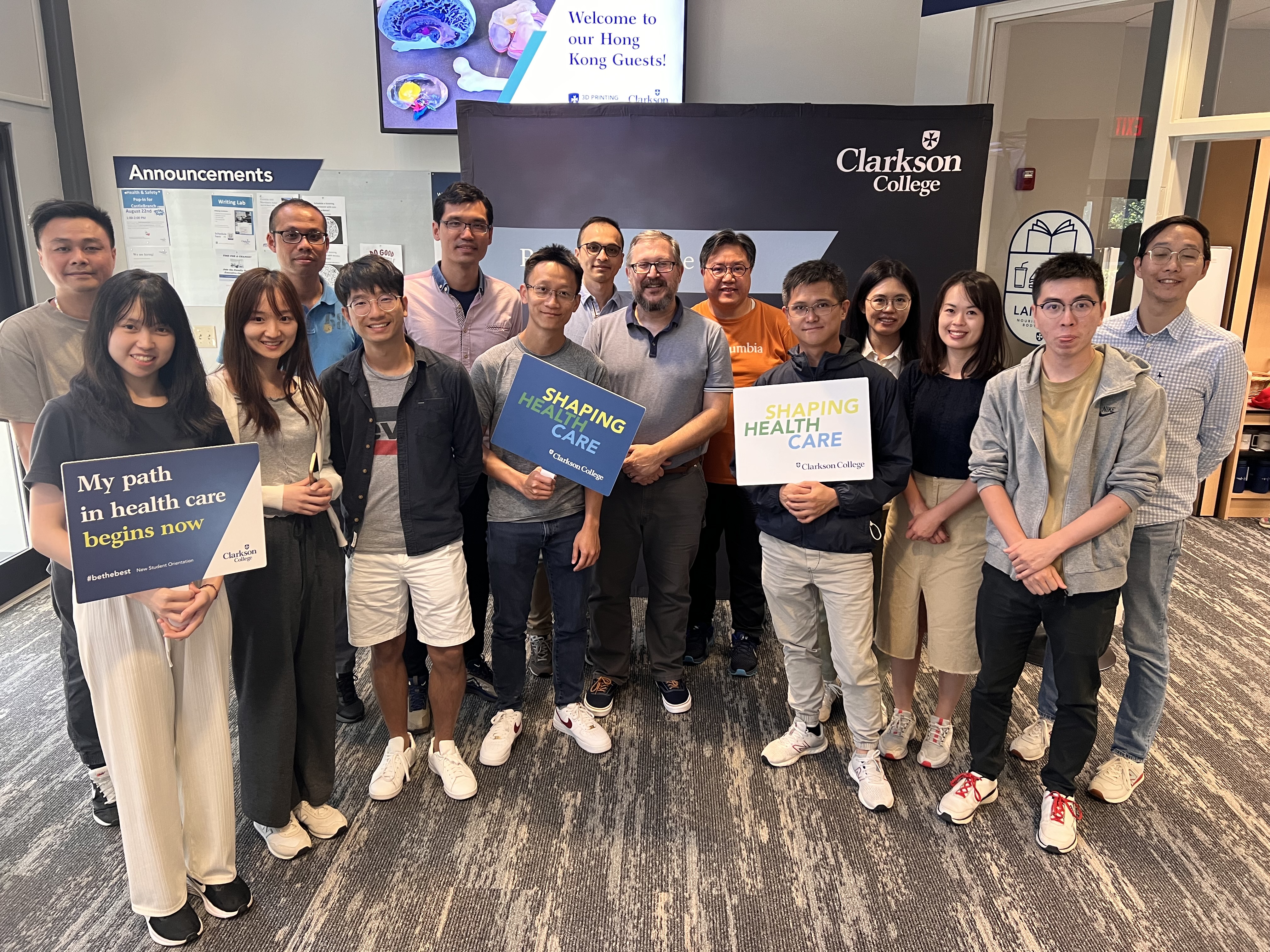 A posed group photo, multiple individuals holding signs promoting the 3d printing department.